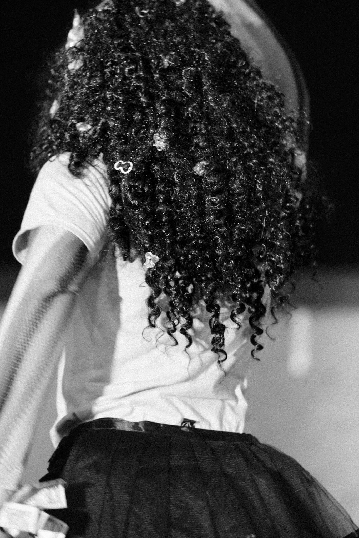 Black and white photo showing curly natural hair against white clothing.