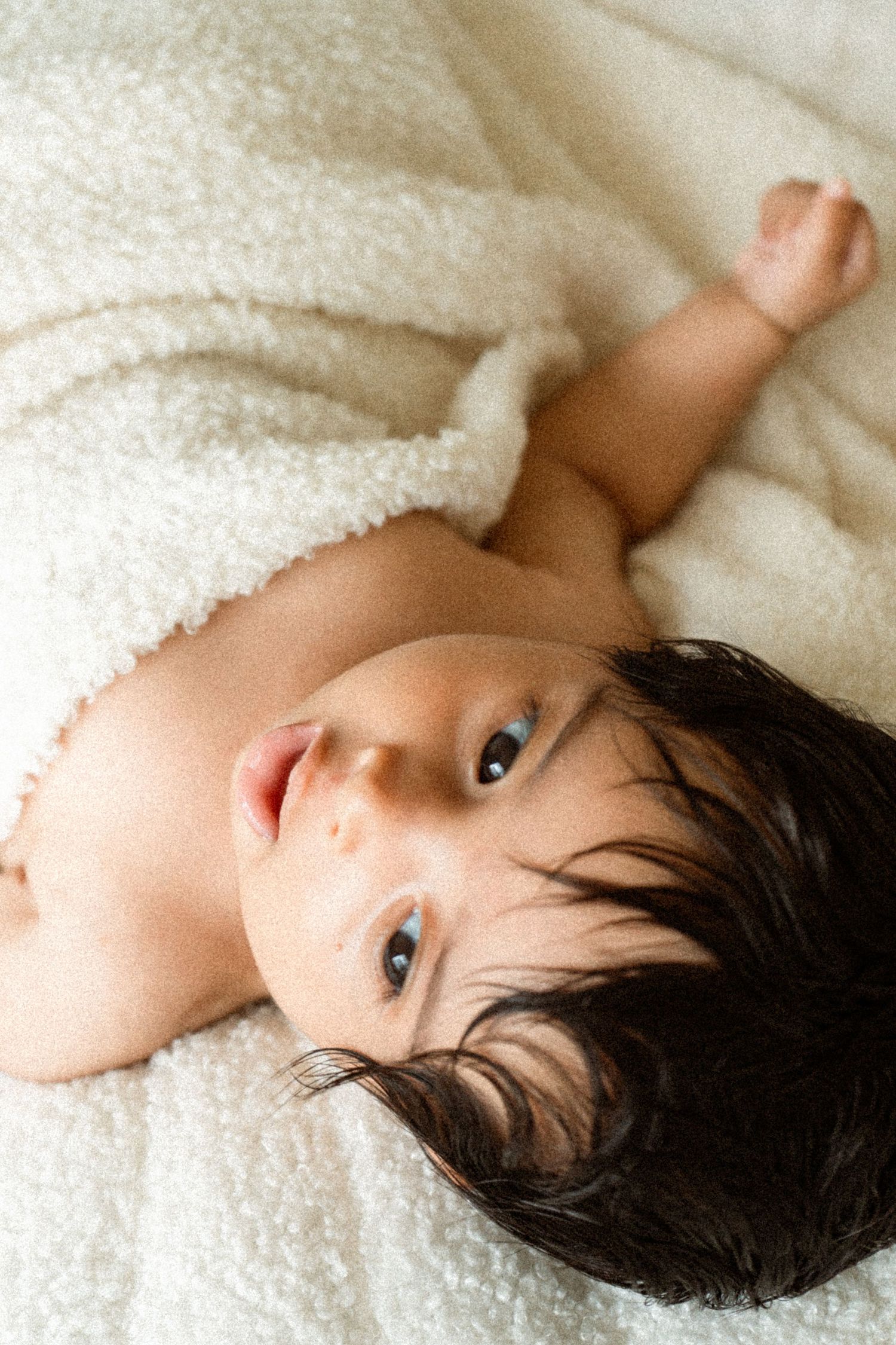 A person lying on soft white bedding with dark hair against a light background.