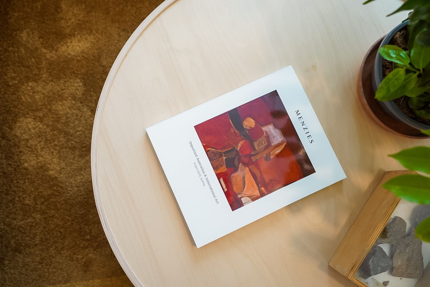 A red photo album displayed on a round white table with potted plant.
