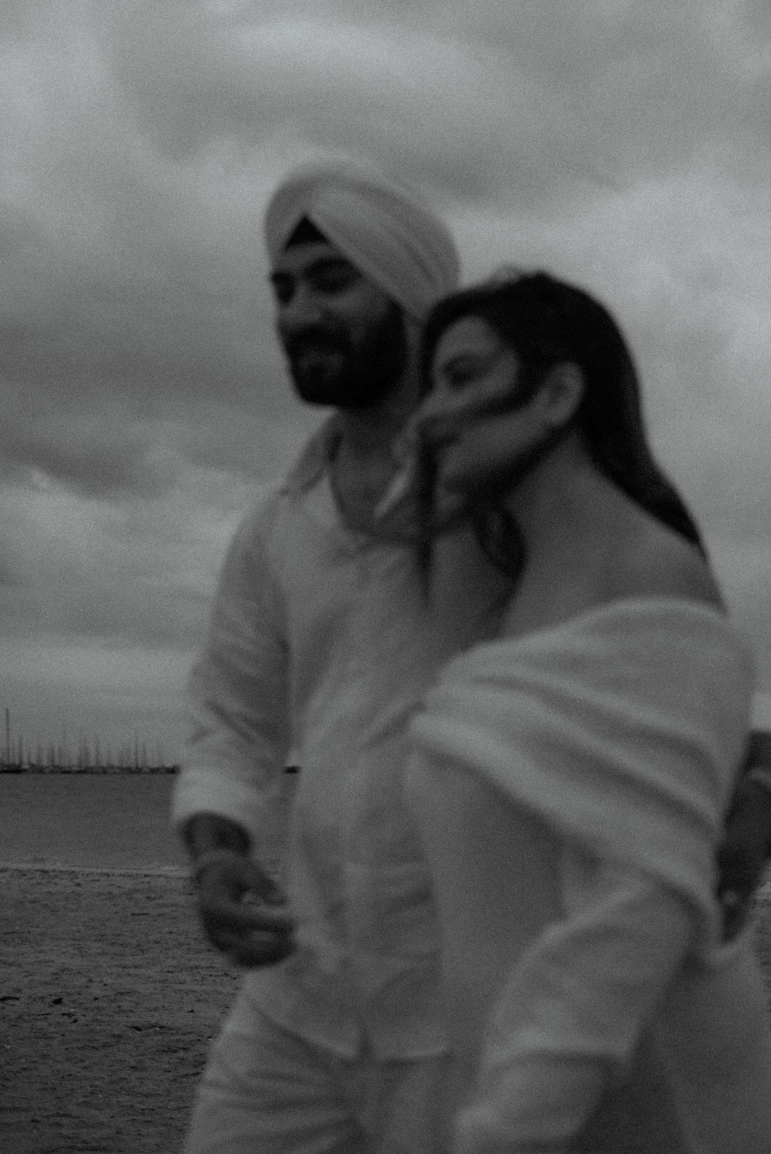 Romantic black and white beach photo of couple in white clothing.