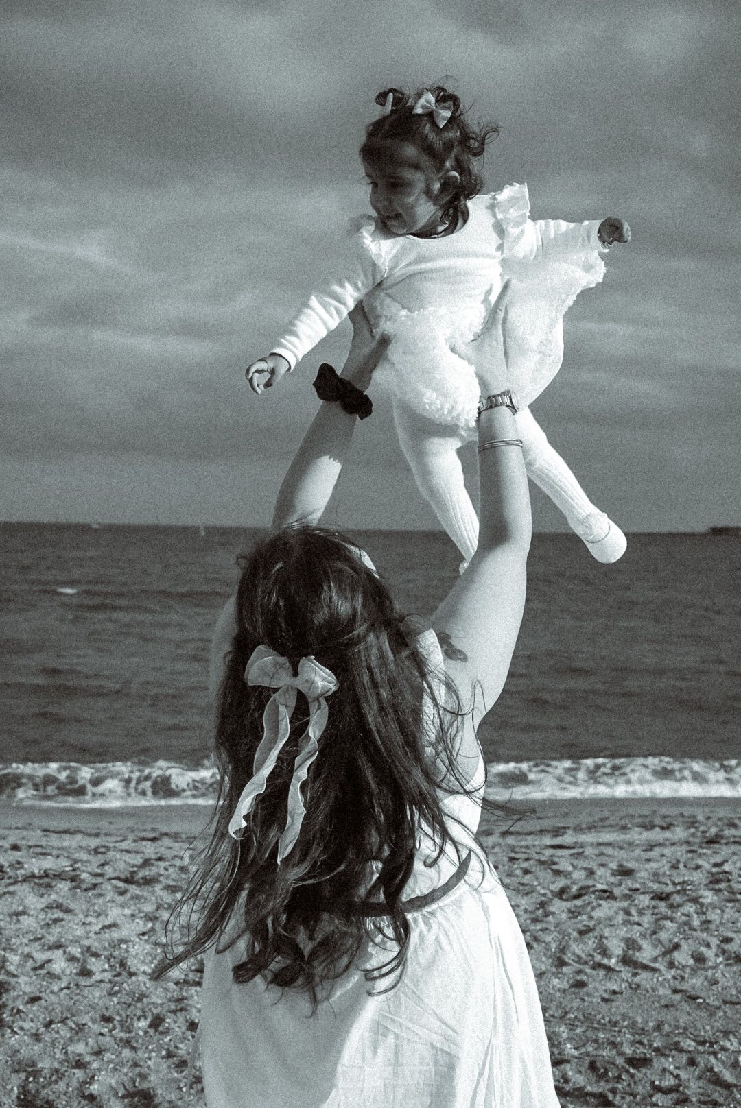 Black and white beach scene with flowing white dress movement.