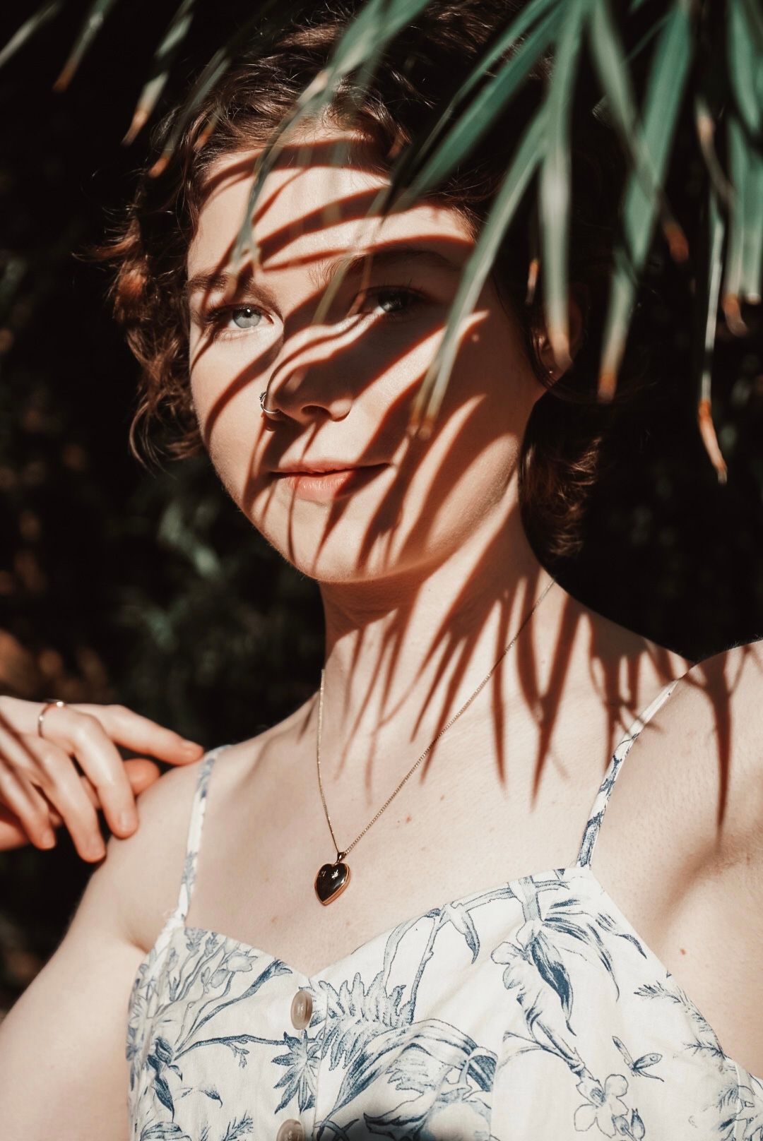 Sunlit portrait with palm leaf shadows casting patterns.