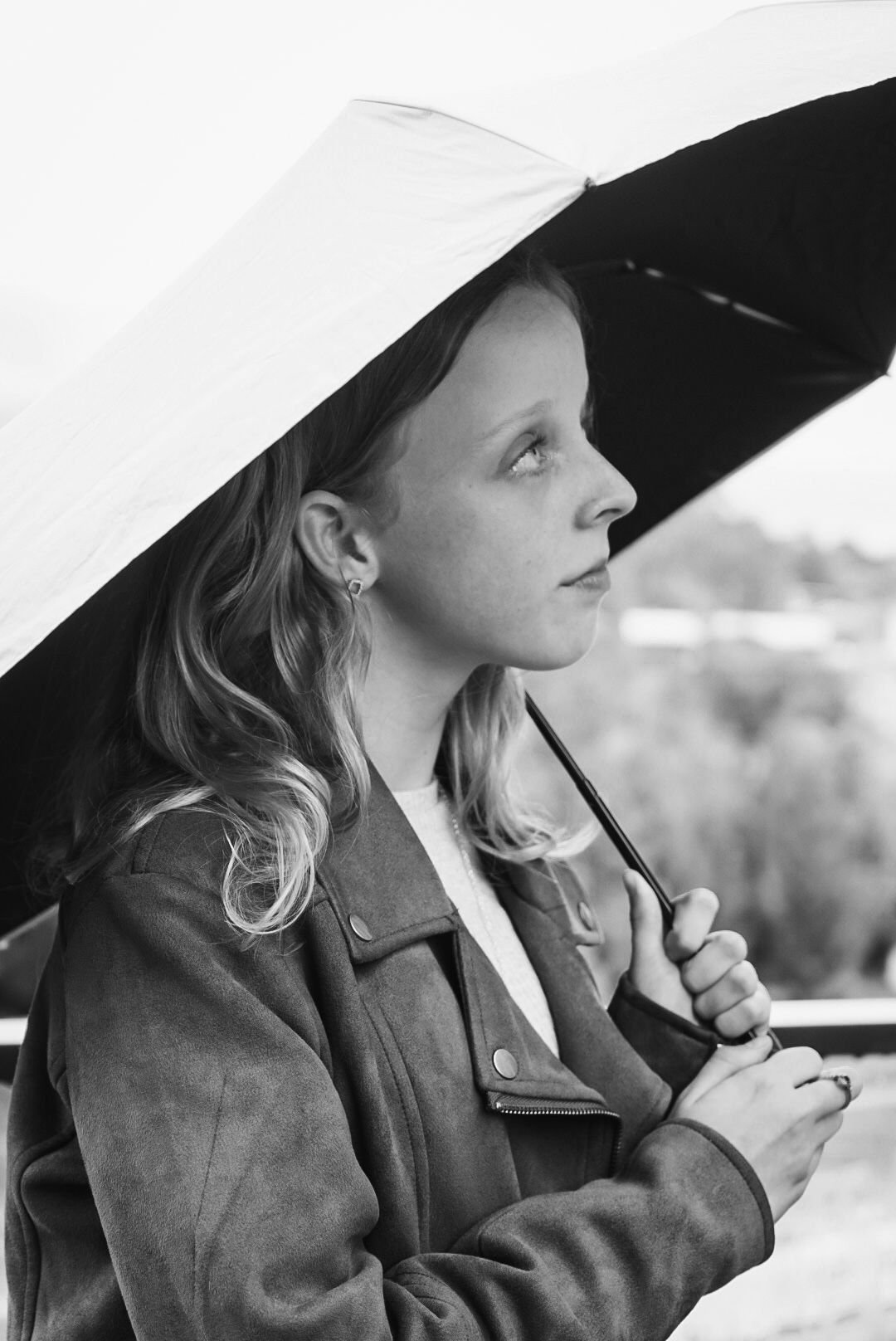 Person wearing a white hat and jacket gazes thoughtfully in black and white portrait.