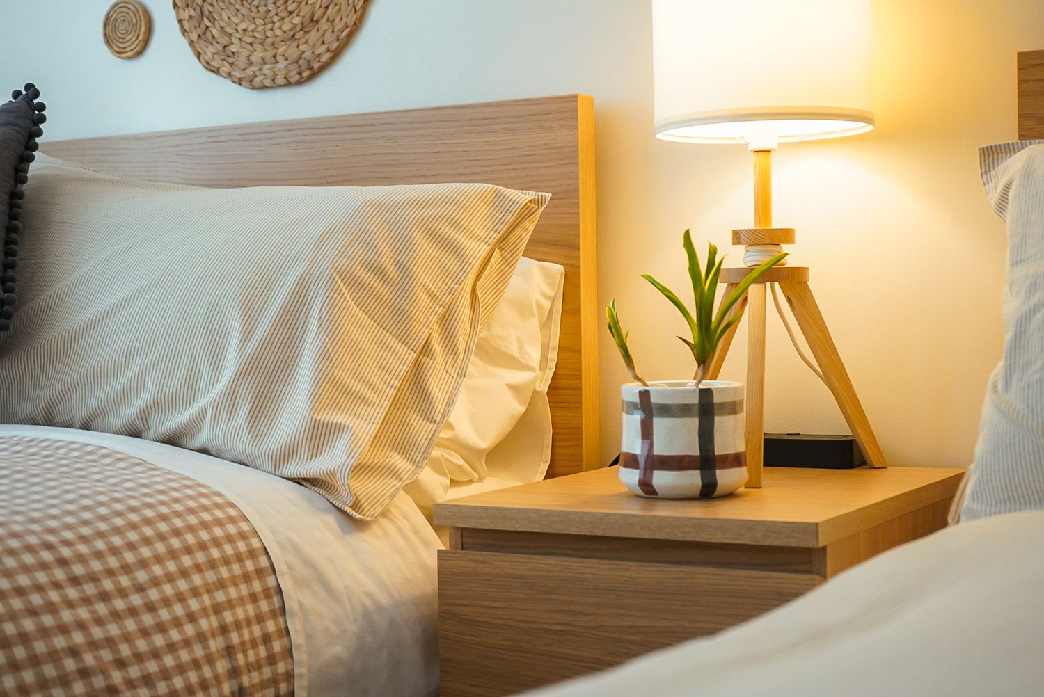 Cozy bedroom interior with warm lighting, plush white bedding, and wooden nightstand with decorative accents.