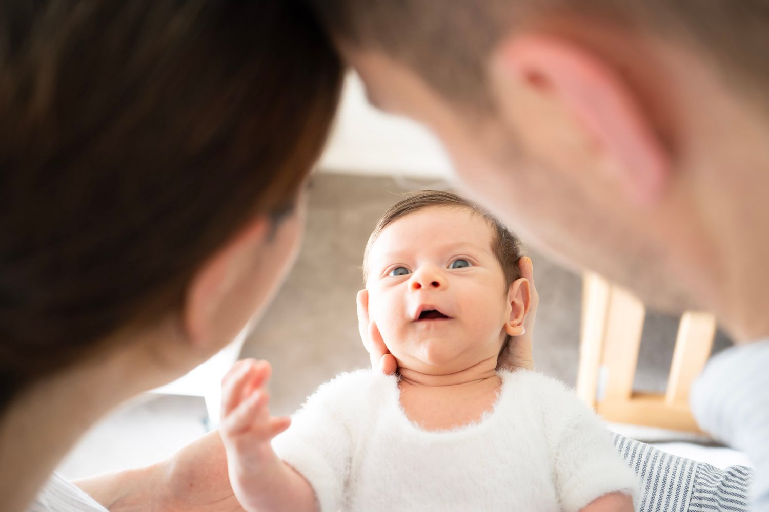 Parents lovingly gazing at their newborn baby in a bright, tender family moment.
