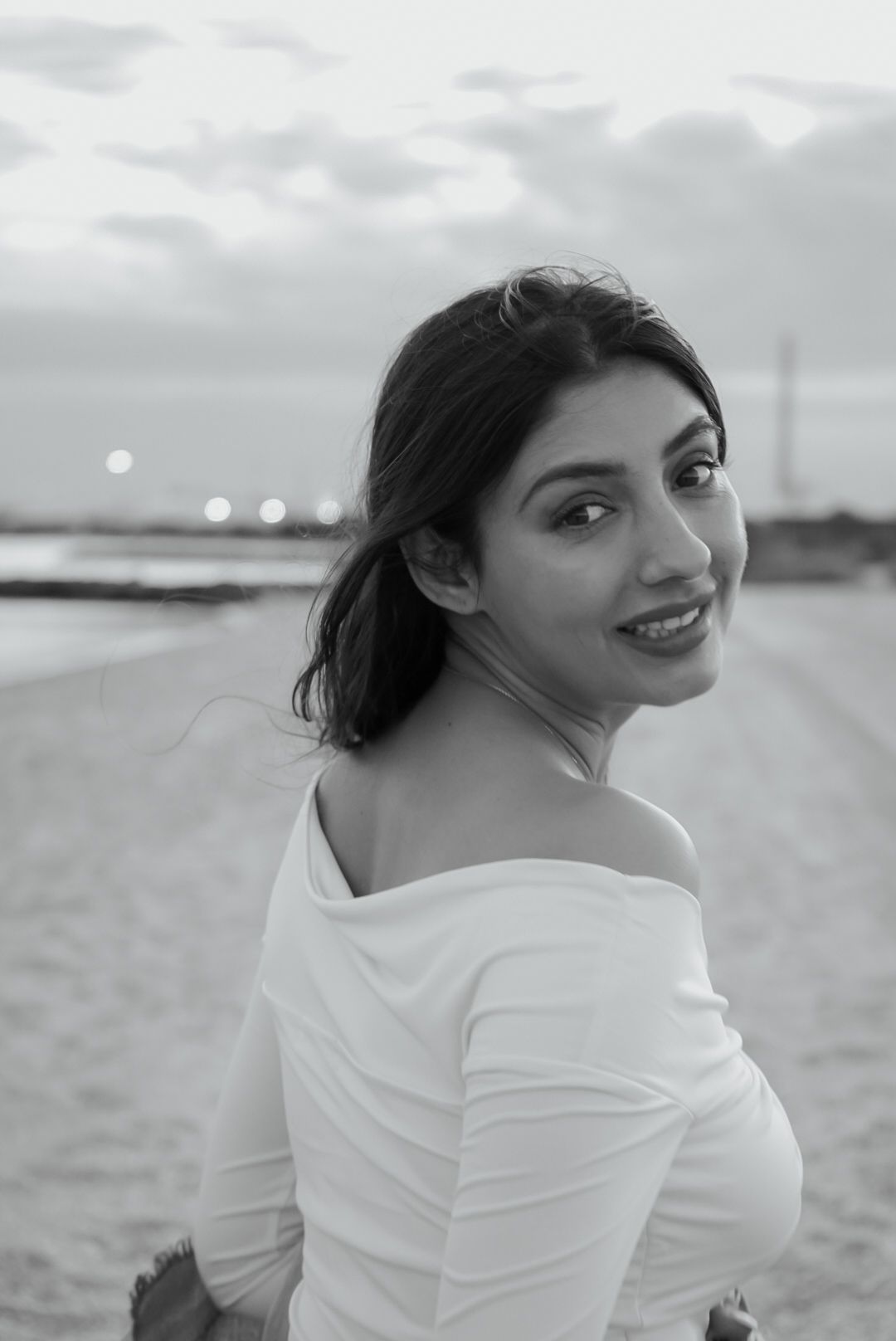 Artistic black and white beach portraits showing joyful expressions and white clothing.