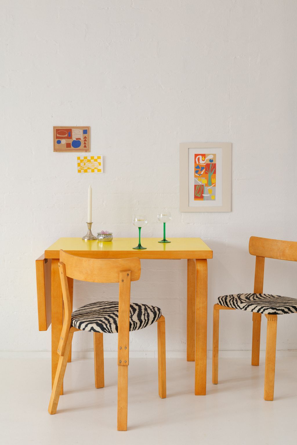 Modern wooden dining table set with zebra print benches and minimalist wall art in a bright white room.
