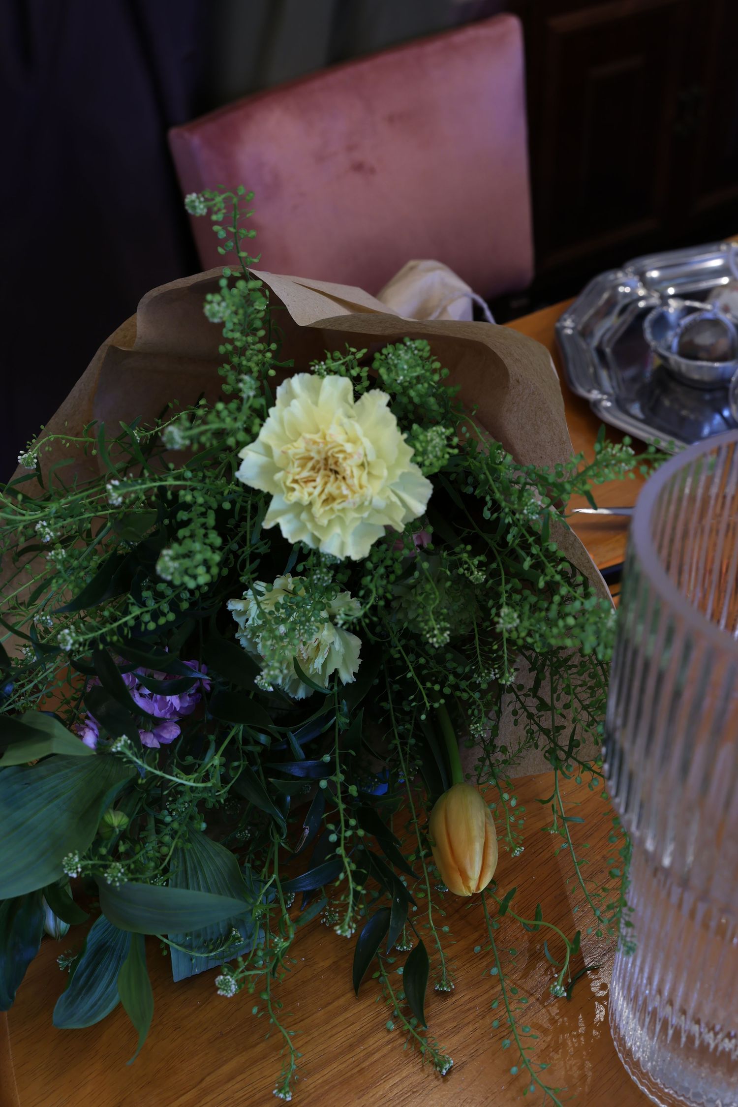 A series of six photos showing a delicate floral arrangement with white carnations and green foliage on a wooden surface.