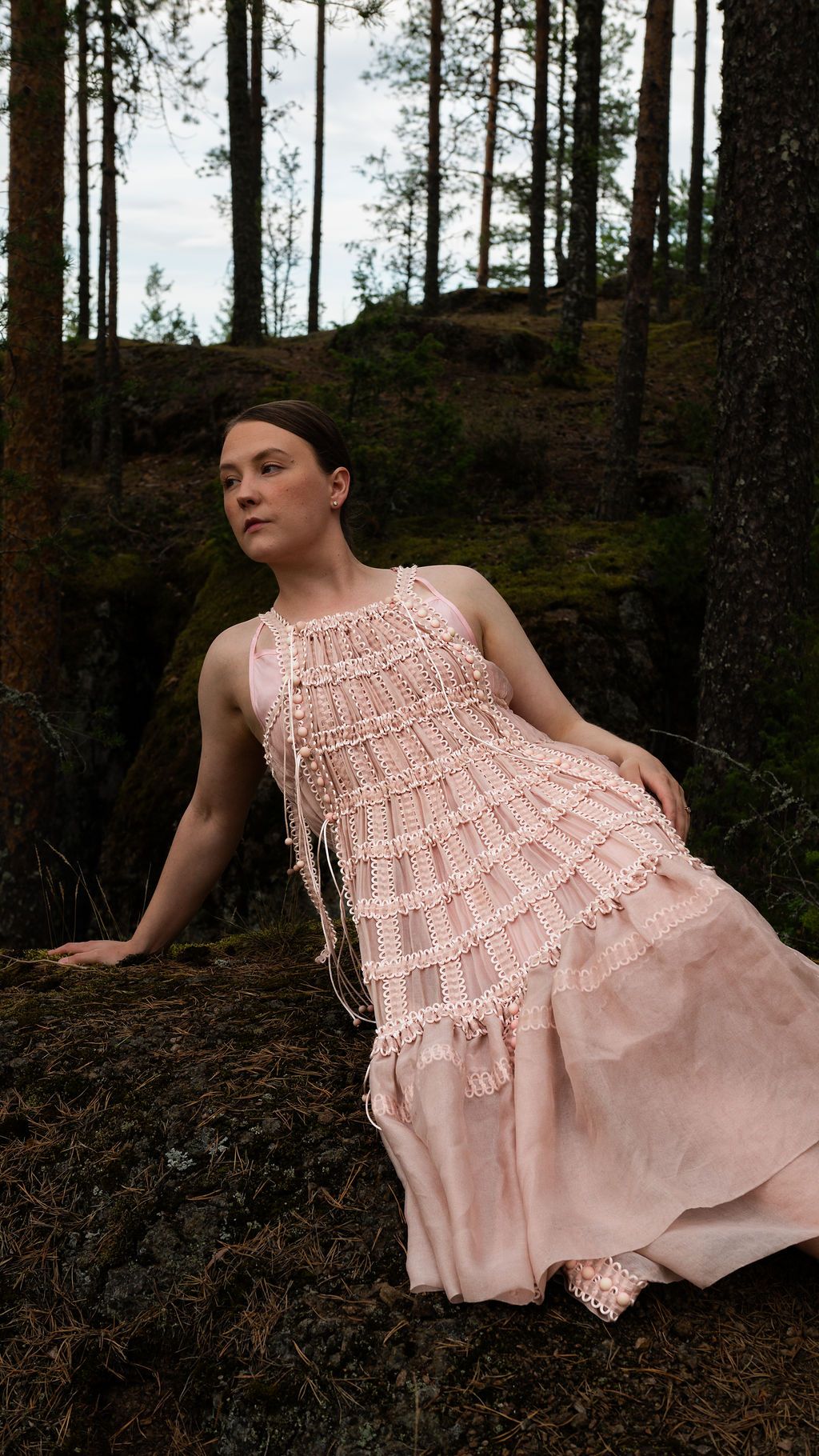 Someone wearing a flowing pink lace dress poses dramatically against a dark forest backdrop in a four-panel photo series.