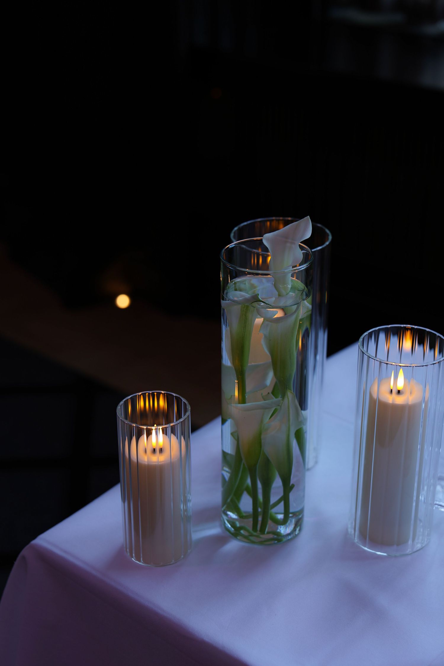 Lit white candles in glass holders create a romantic ambiance against a dark background in this series of photos.