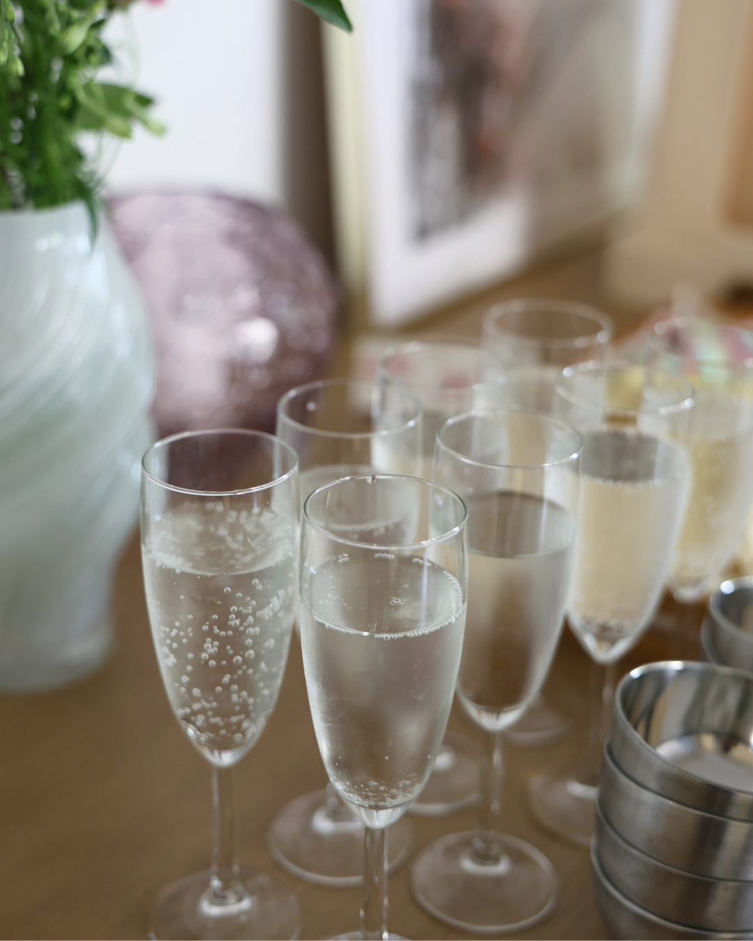 Elegant champagne flutes filled with sparkling wine arranged on a wooden table at a celebration event.