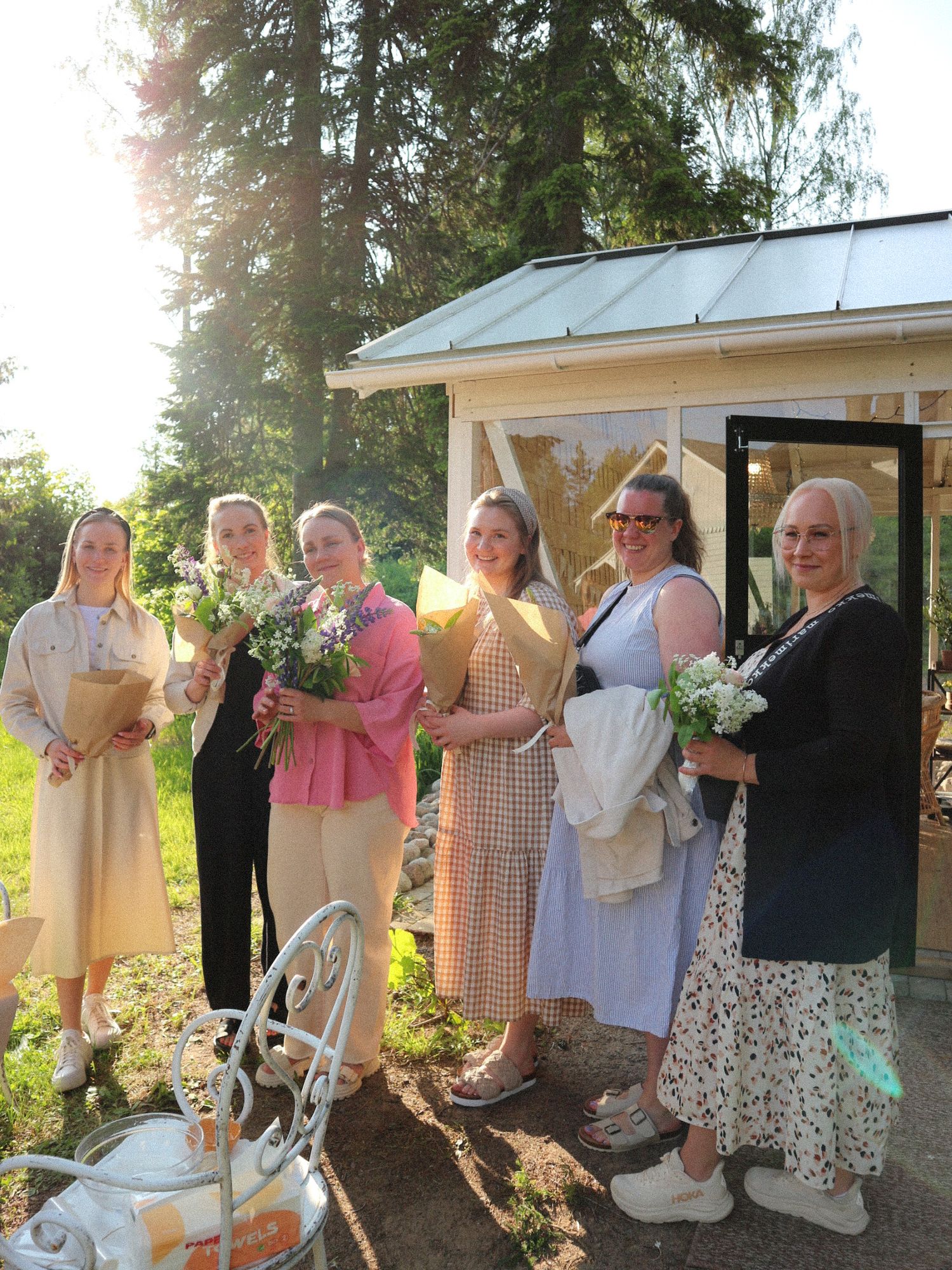 A group of people dancing in a line at an outdoor garden party during sunset.
