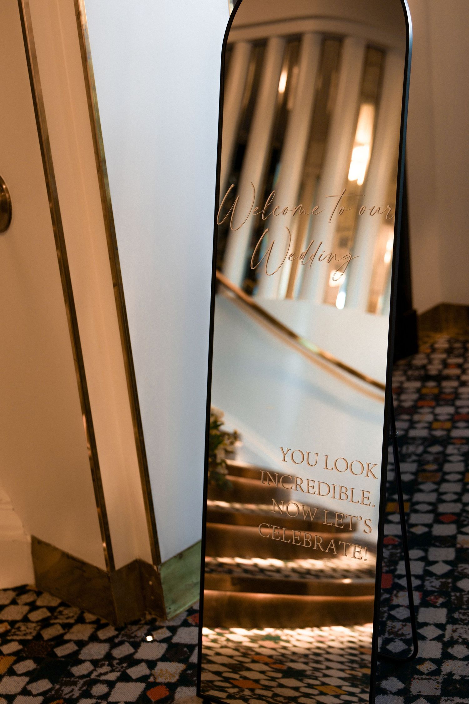 A decorative mirror with text 'You Look Incredible' reflects warm lighting on a patterned floor.