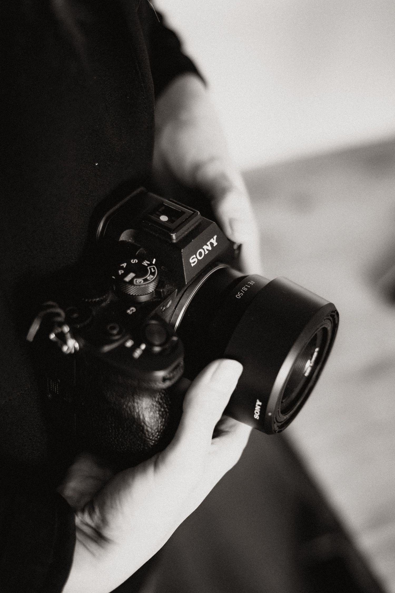 Person holding a Sony mirrorless camera in black and white photography.