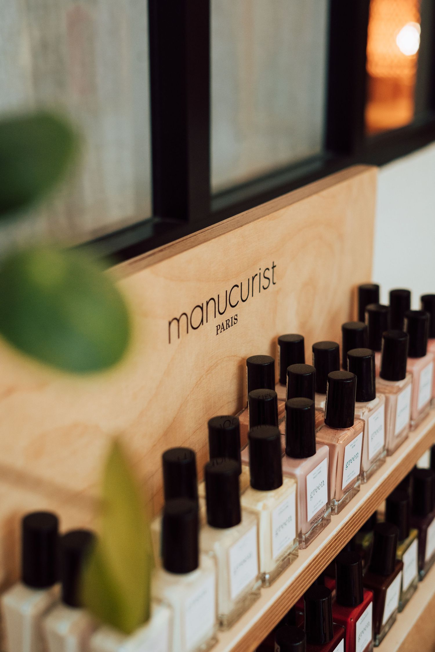 Manucurist Paris nail polish bottles displayed on wooden shelves in a boutique salon setting.