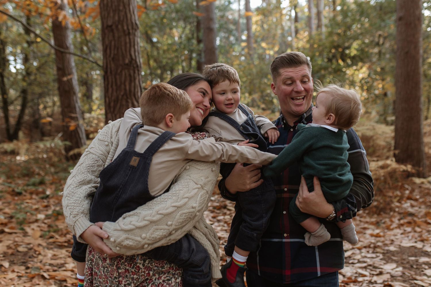 Happy family of five sharing a warm group hug among autumn trees in a forest.
