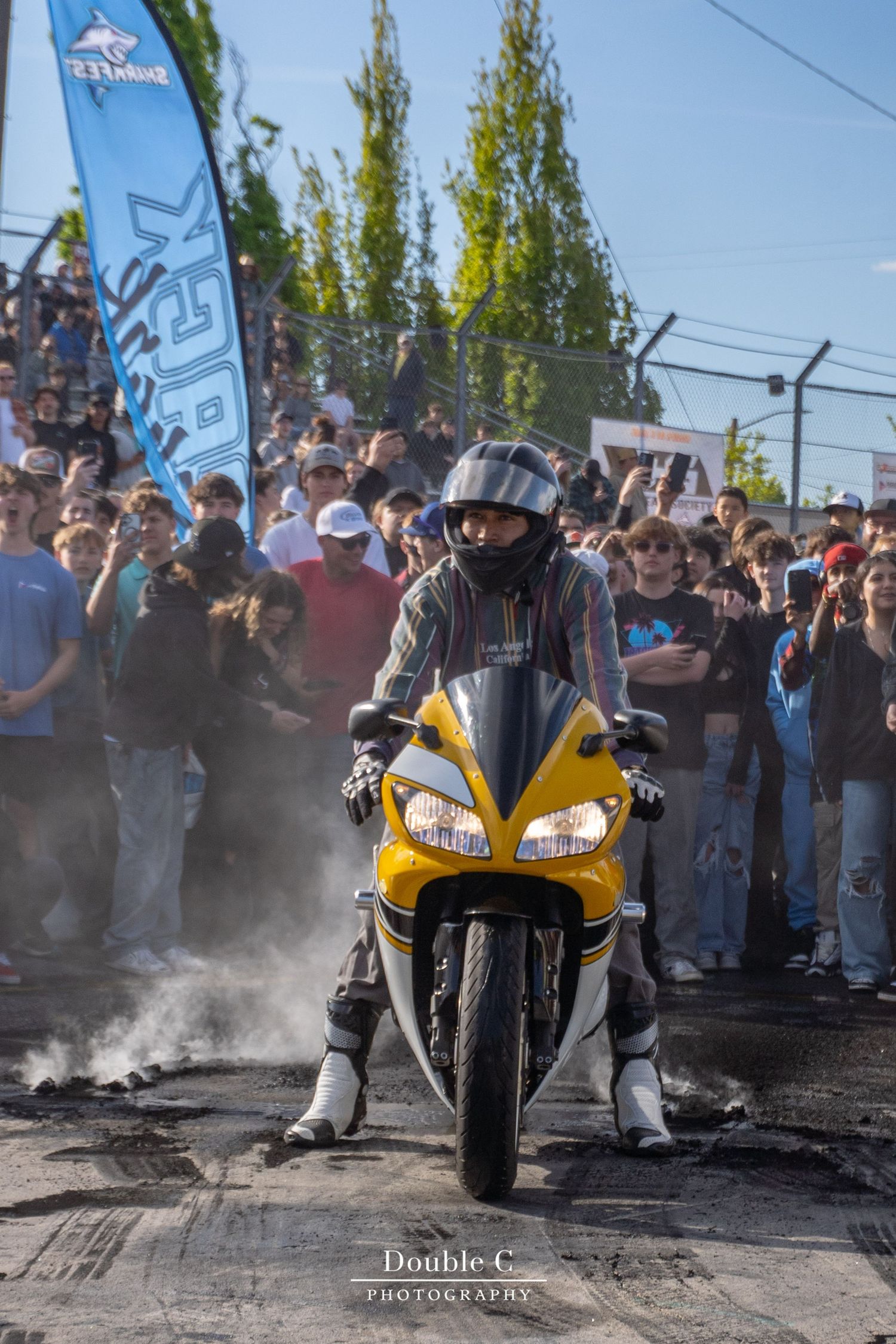 Yellow motorcycle performing a burnout in front of spectators during the Track Shark Season Opener in Idaho