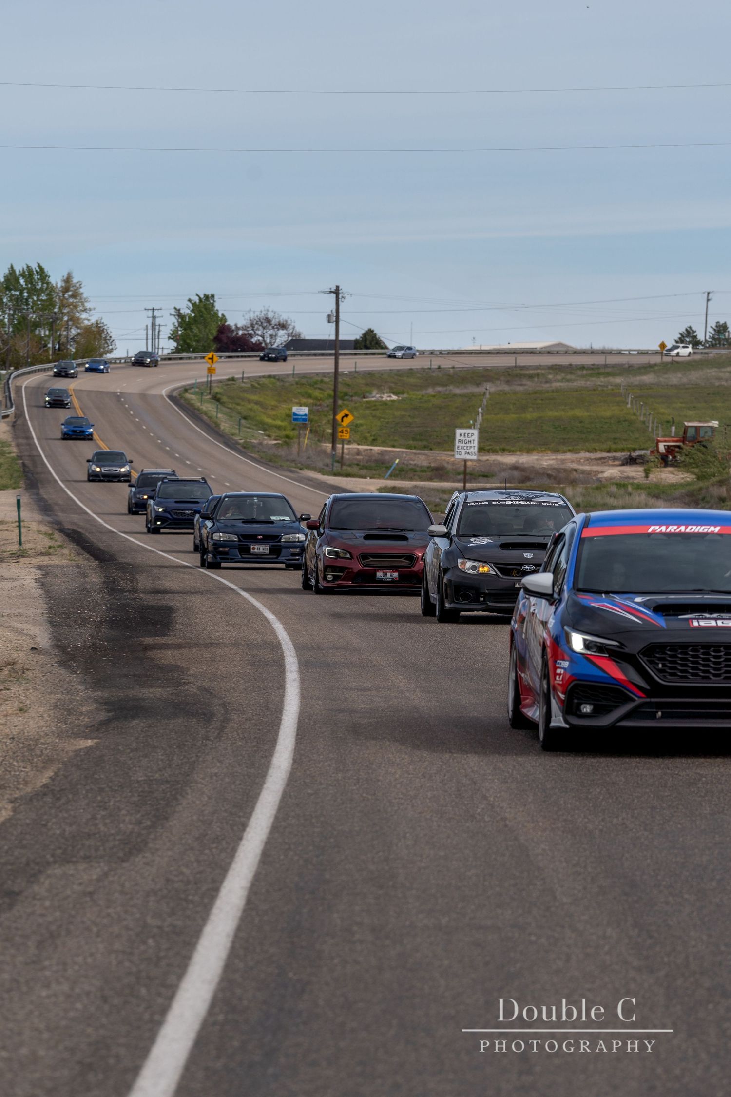 Line of Subaru vehicles driving an Idaho road during an Idaho Subaru Club cruise