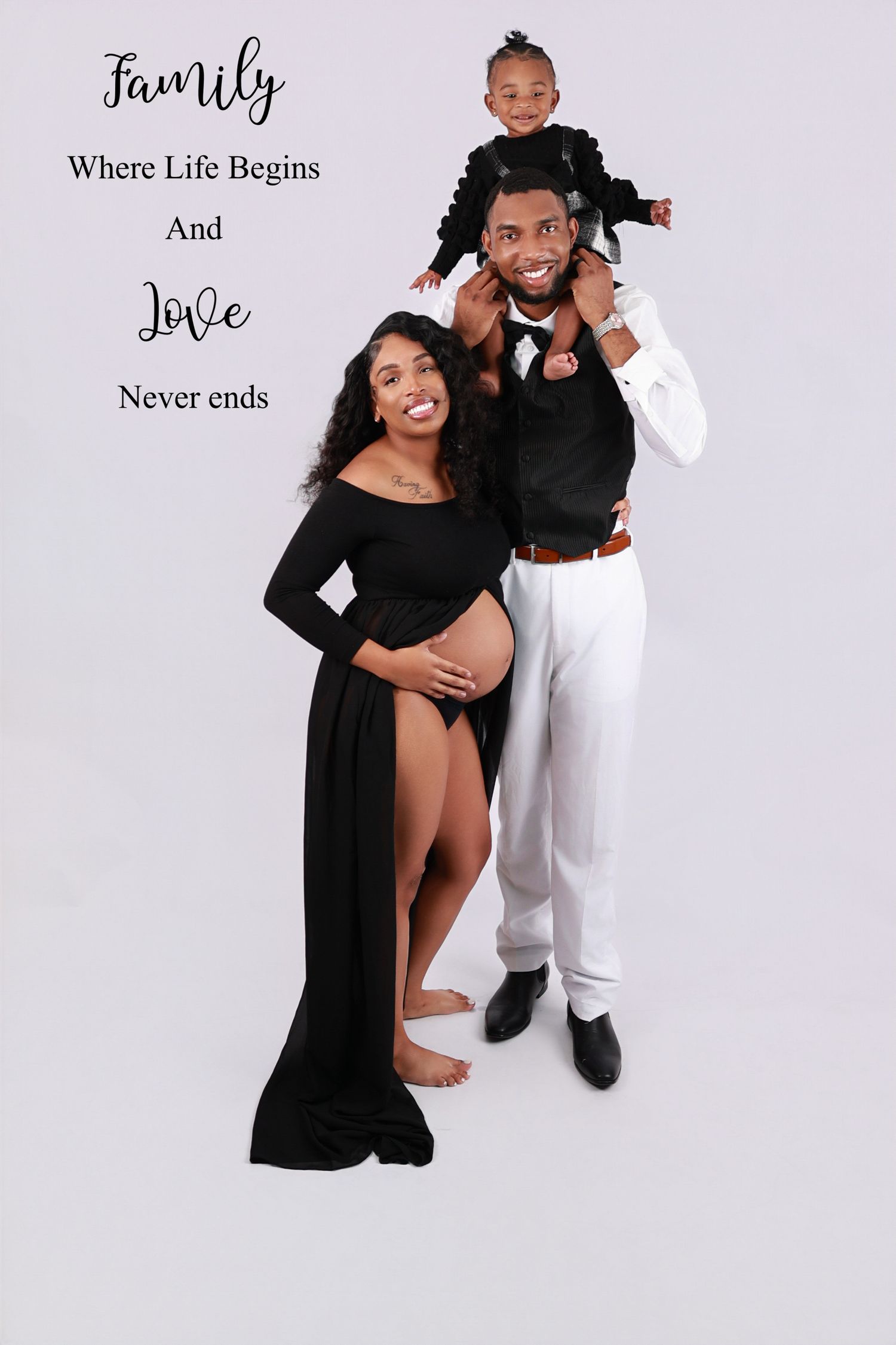 Pregnant woman in black gown poses with husband and toddler for a family maternity portrait.