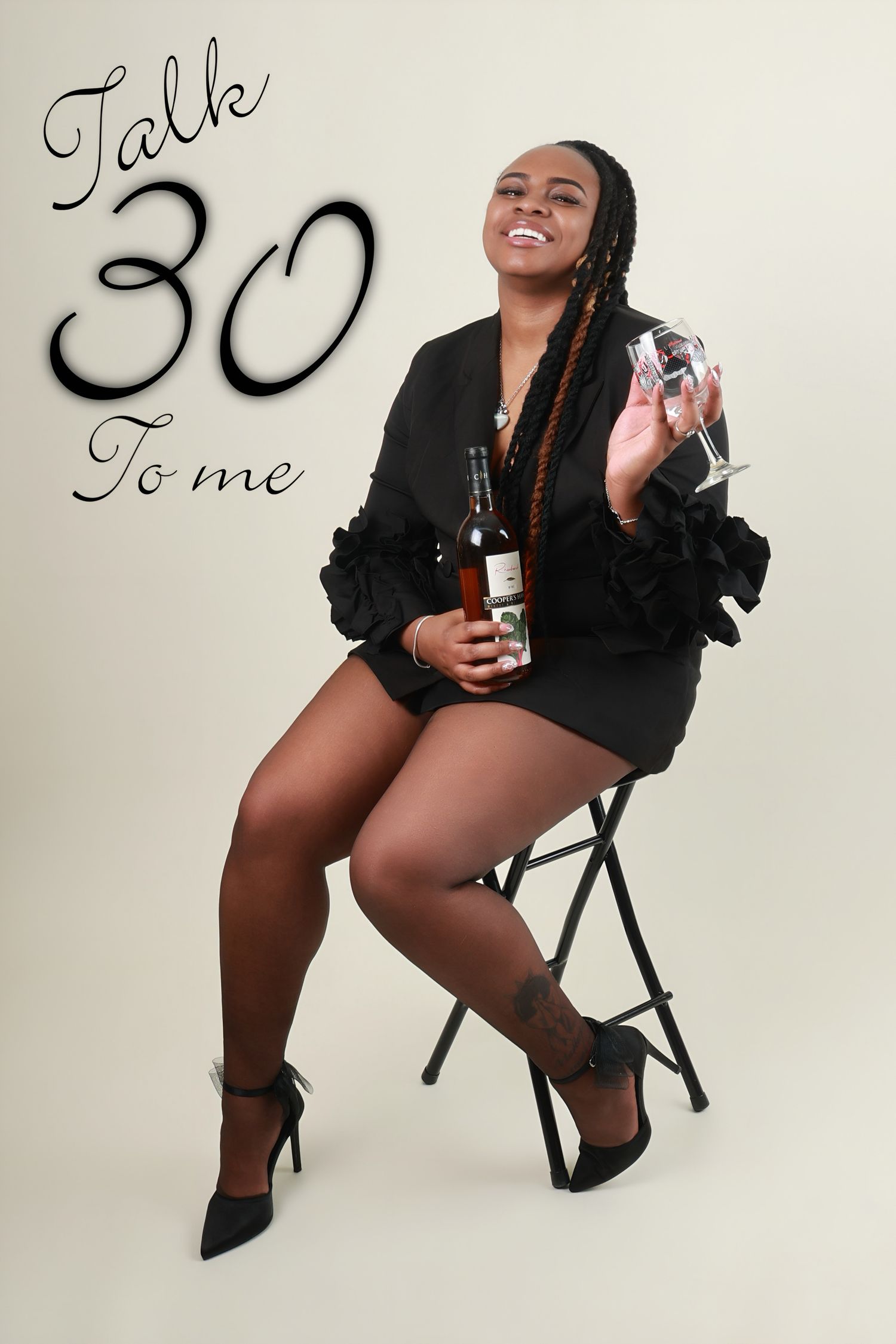 Woman celebrating 30th birthday in black dress holding wine bottle and glass with Talk 30 To Me text.