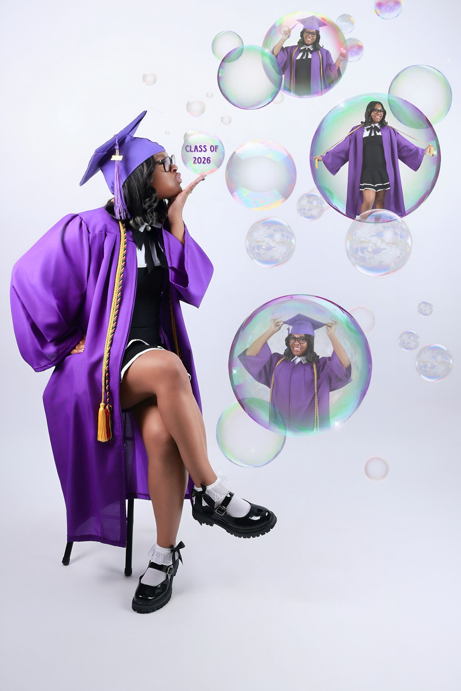 Graduate in purple cap and gown blowing bubbles showing Class of 2026 sign.