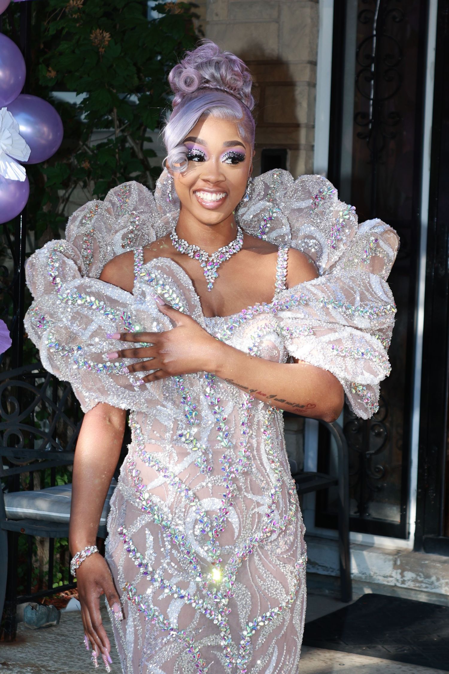 Woman in sparkly silver gown with puff sleeves and lavender updo at formal event.