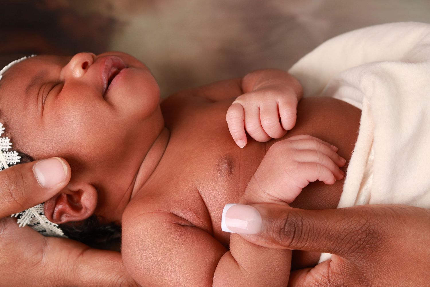 Close-up of a peaceful sleeping newborn baby being gently held by adult hands.