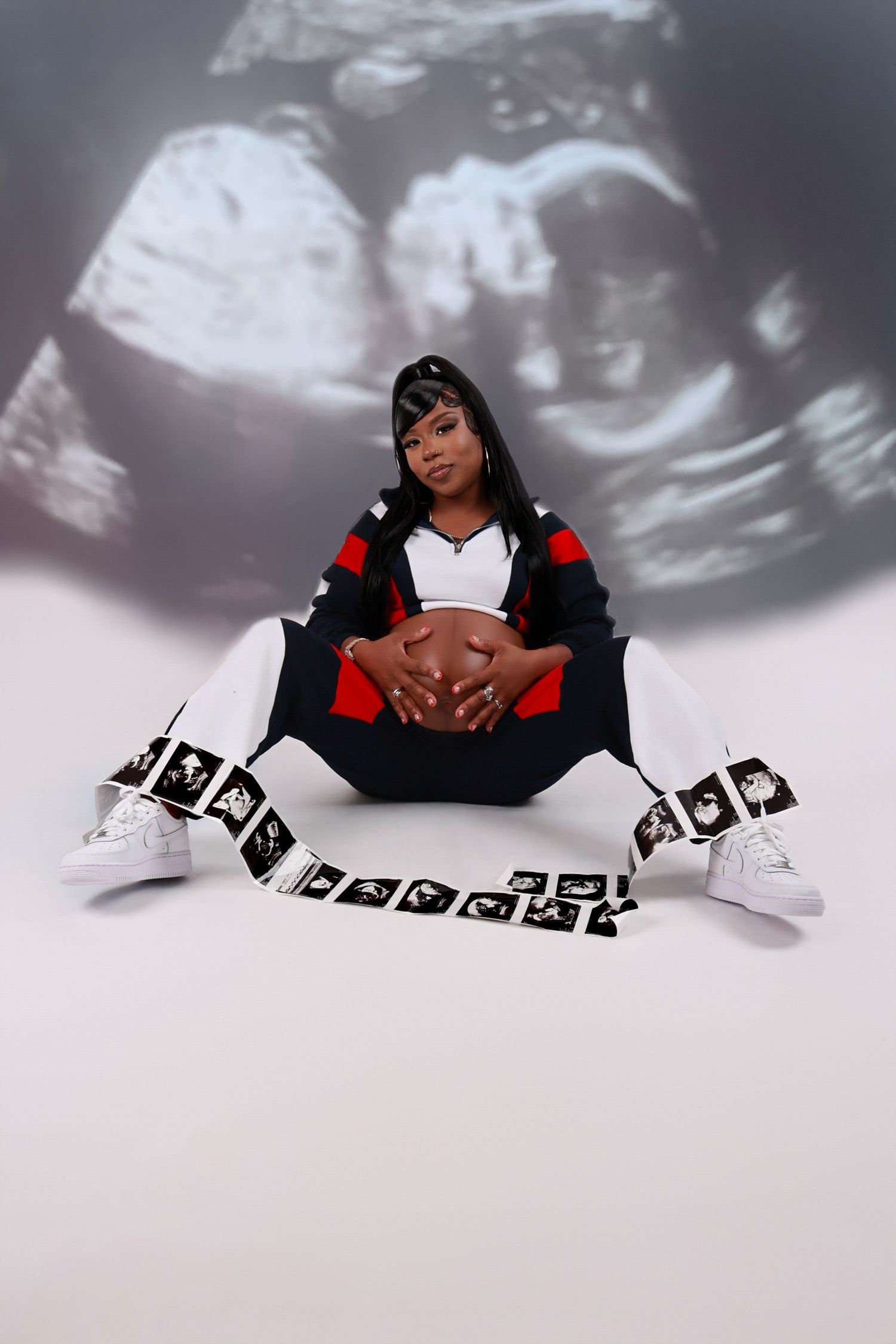 Pregnant woman sits with football surrounded by ultrasound images in a sports-themed maternity shoot.