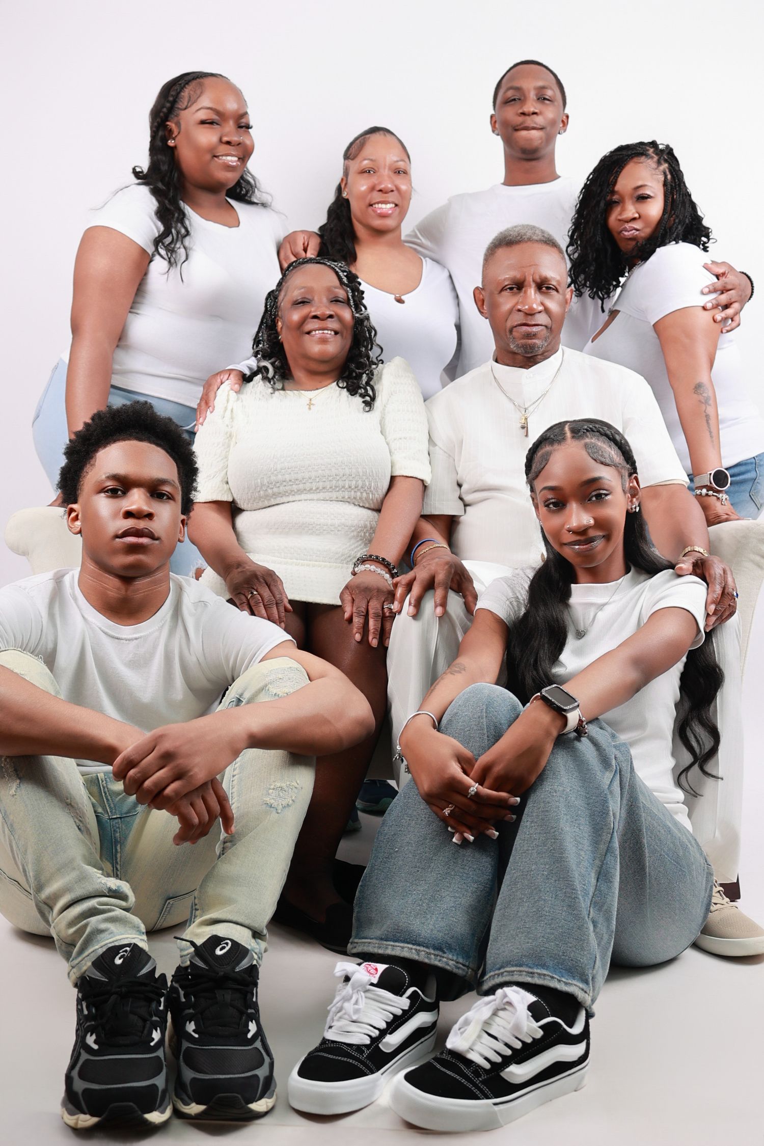 Multi-generational family portrait in coordinating white outfits against white background.