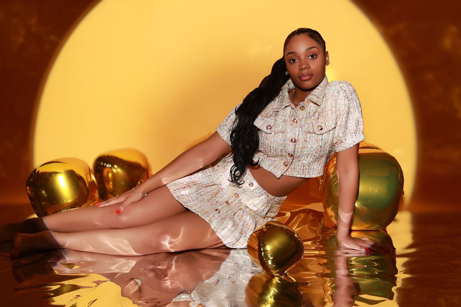 Woman posing with gold balloons on reflective surface.