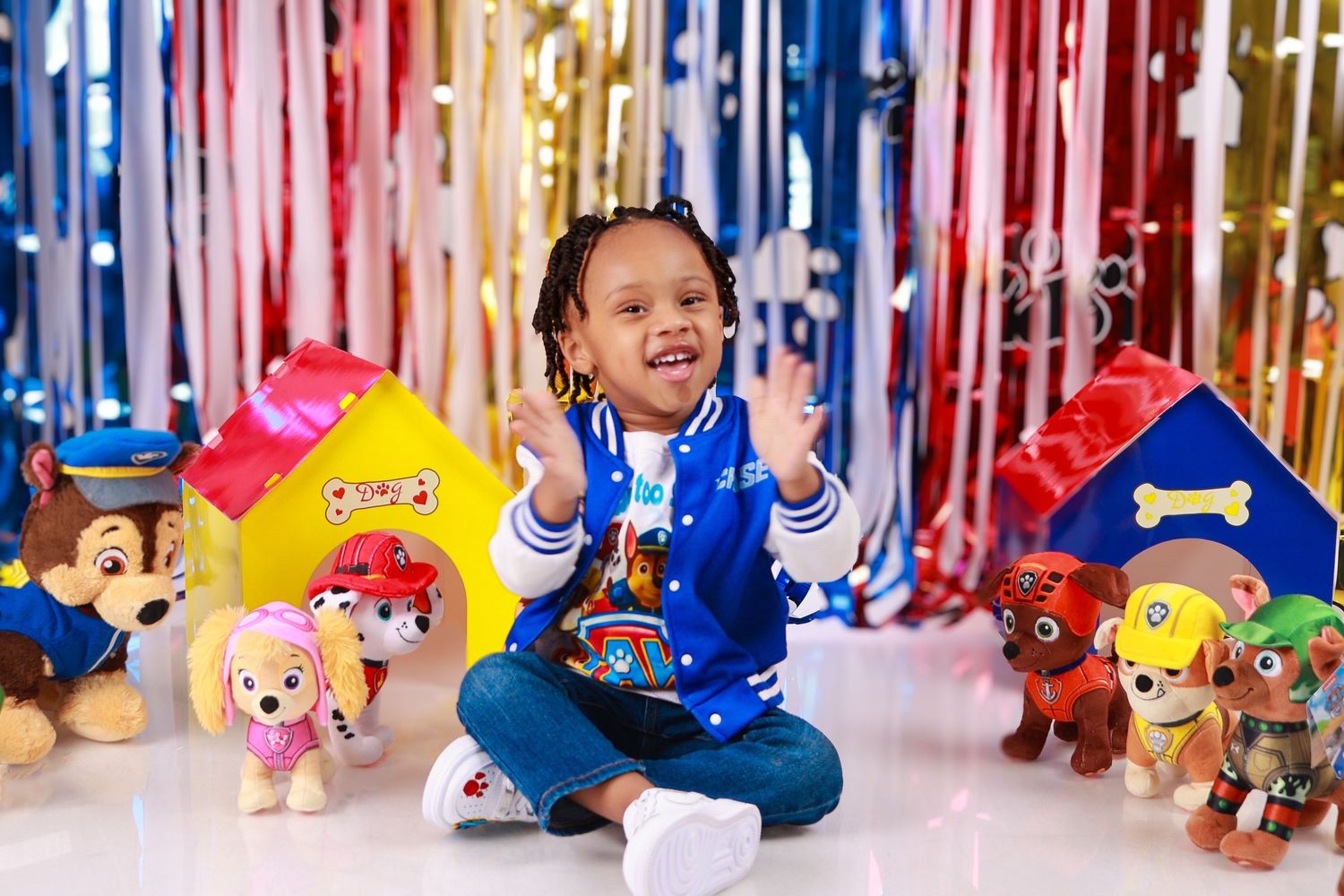 Young child in PAW Patrol themed birthday photo with colorful decorations and character toys.