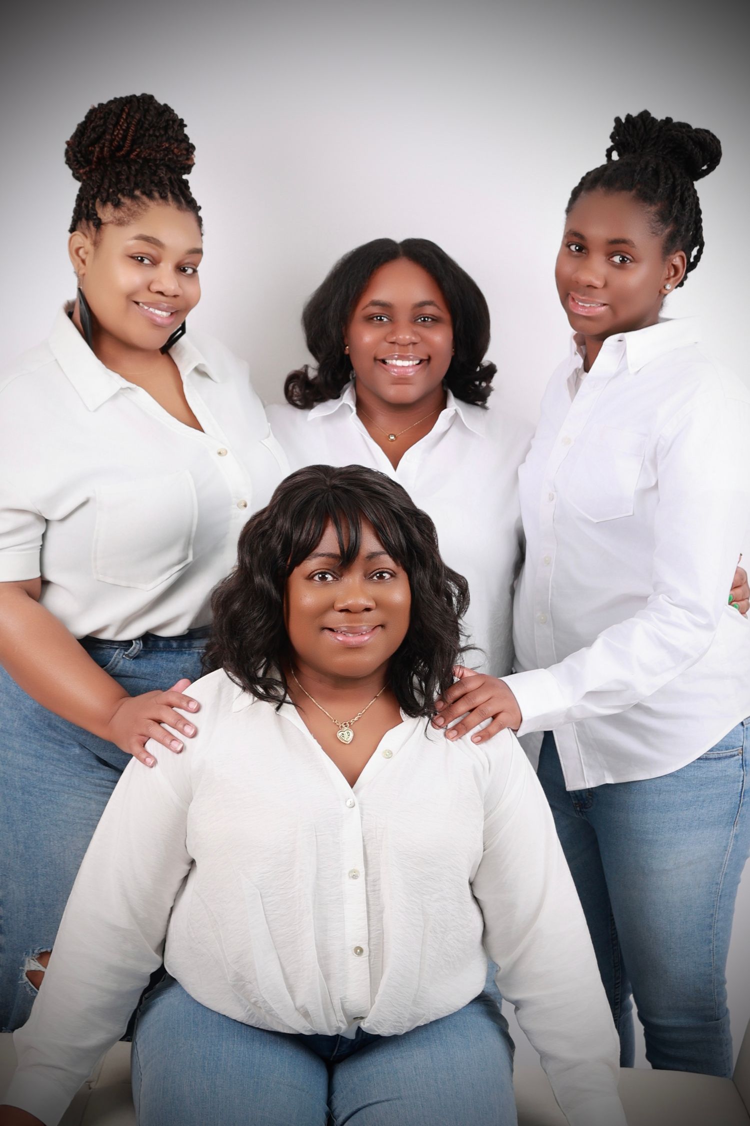 Four  women in white shirts and jeans pose together for a family portrait.