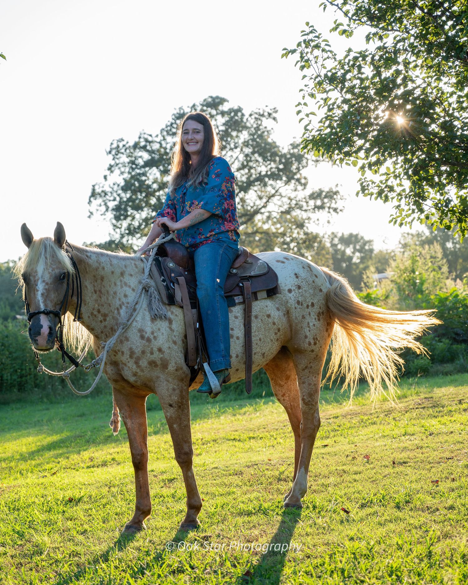 Woman on horseback backlit by sunlight.