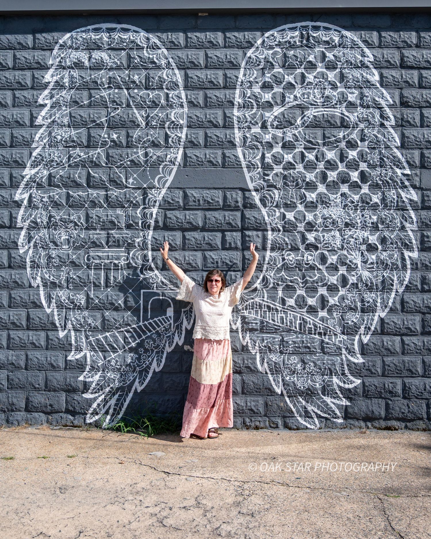 Woman standing in front of artistically painted mural of angel wings.