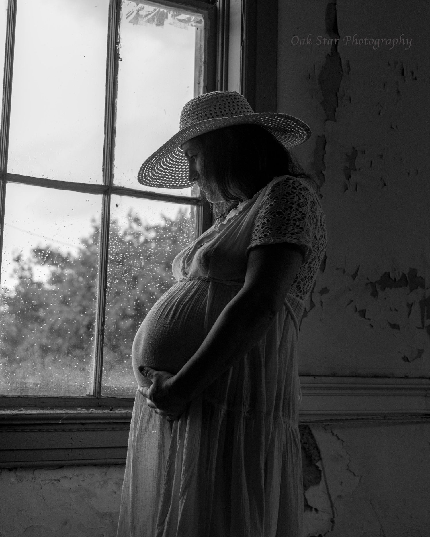 pregnant woman in hat and gown in front of a window