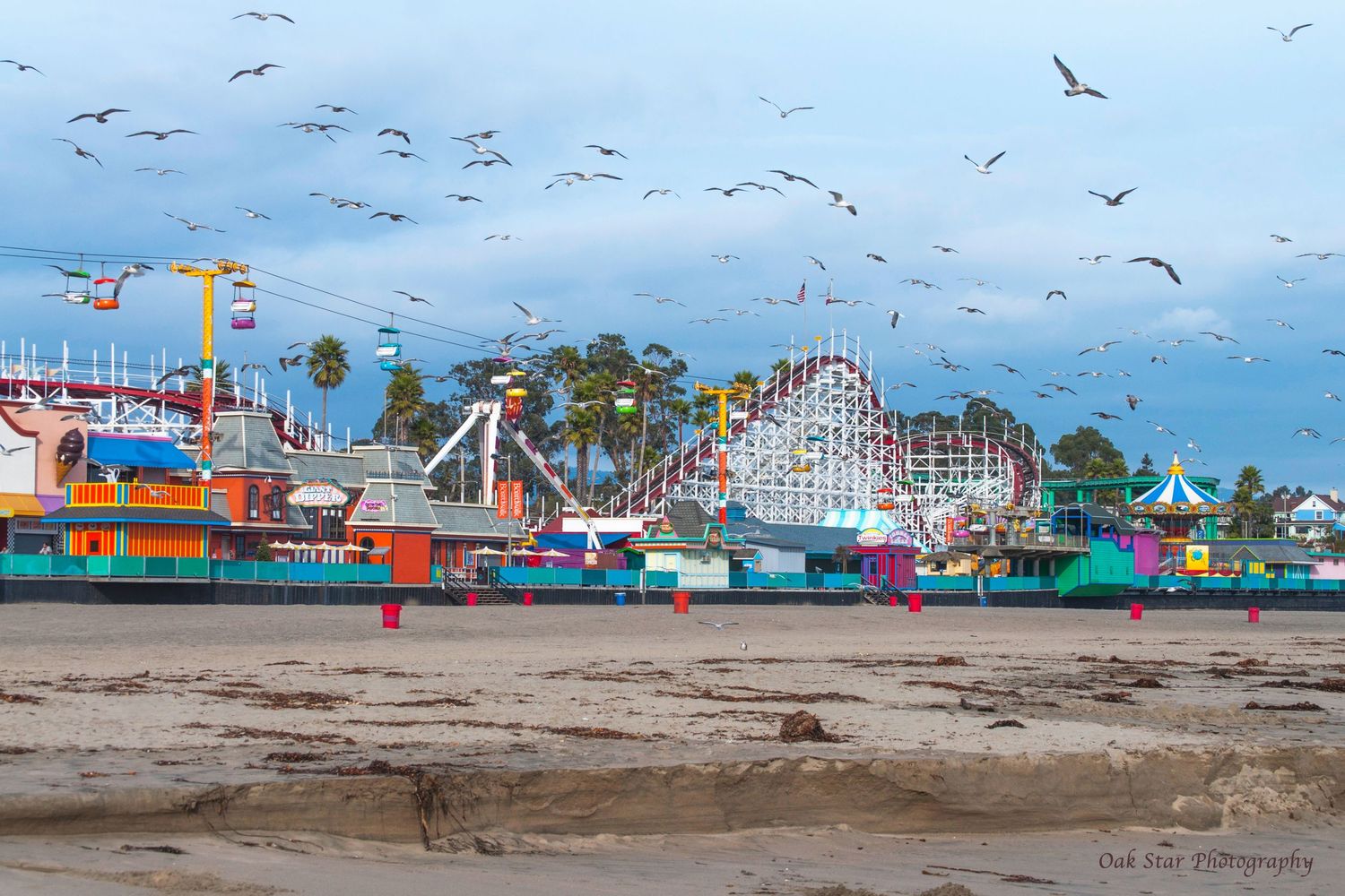 Beach boardwalk in the off season with beach sand in the foreground and birds flying above