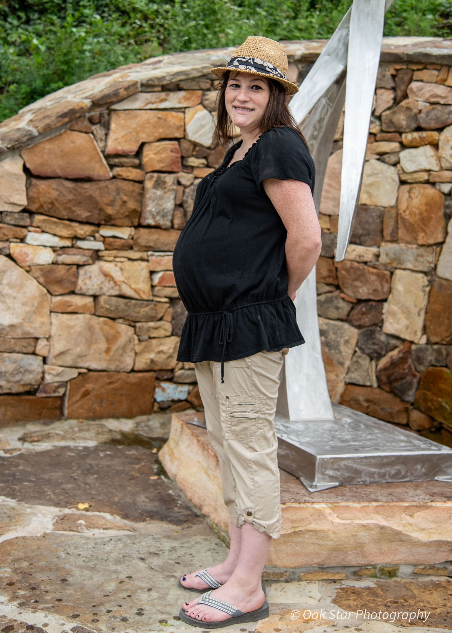 Pregnant woman posing in front of a sculpture.