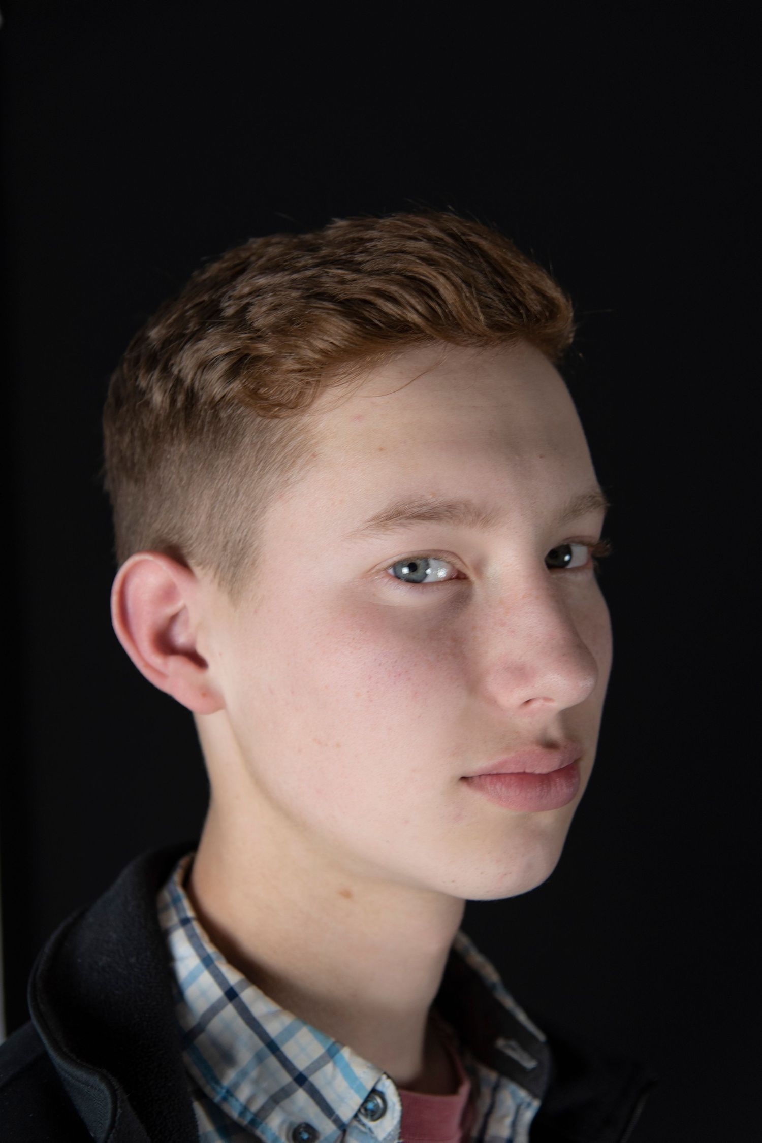 Studio portrait of a young man using side lighting and a black background.
