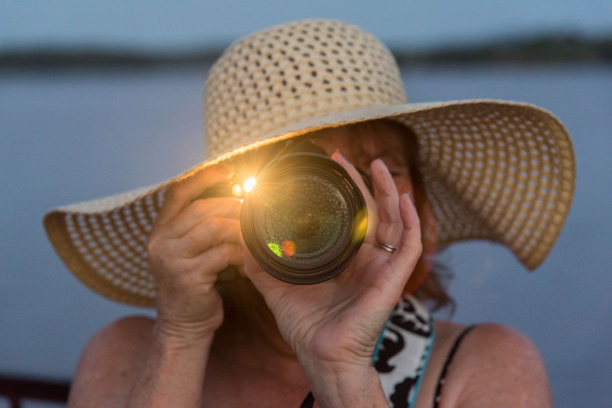 woman with hat looking through a camera