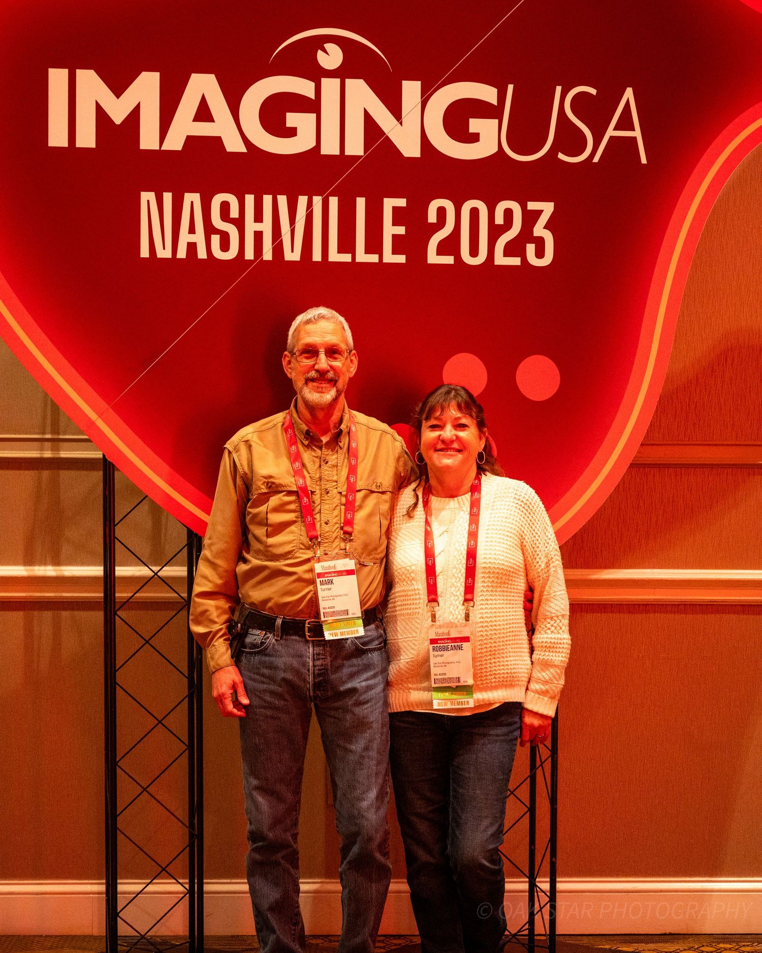 Photographers Mark and Robbie standing in front of the conference logo at ImagingUSA 2023 in Nashville, TN