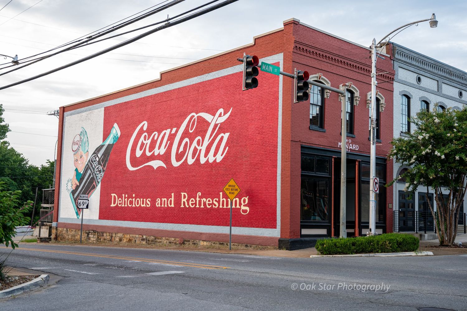 Historic Coca-Cola mural painted on the side of a downtown building on a street corner.