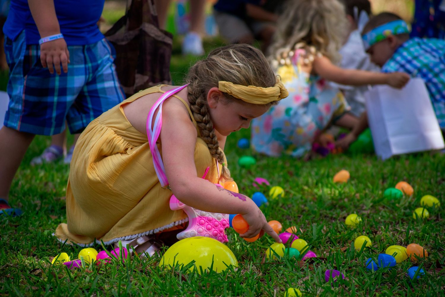 A girl smiles while collecting eggs. Event photography for church & community gatherings. We capture the fun of Easter egg hunts!