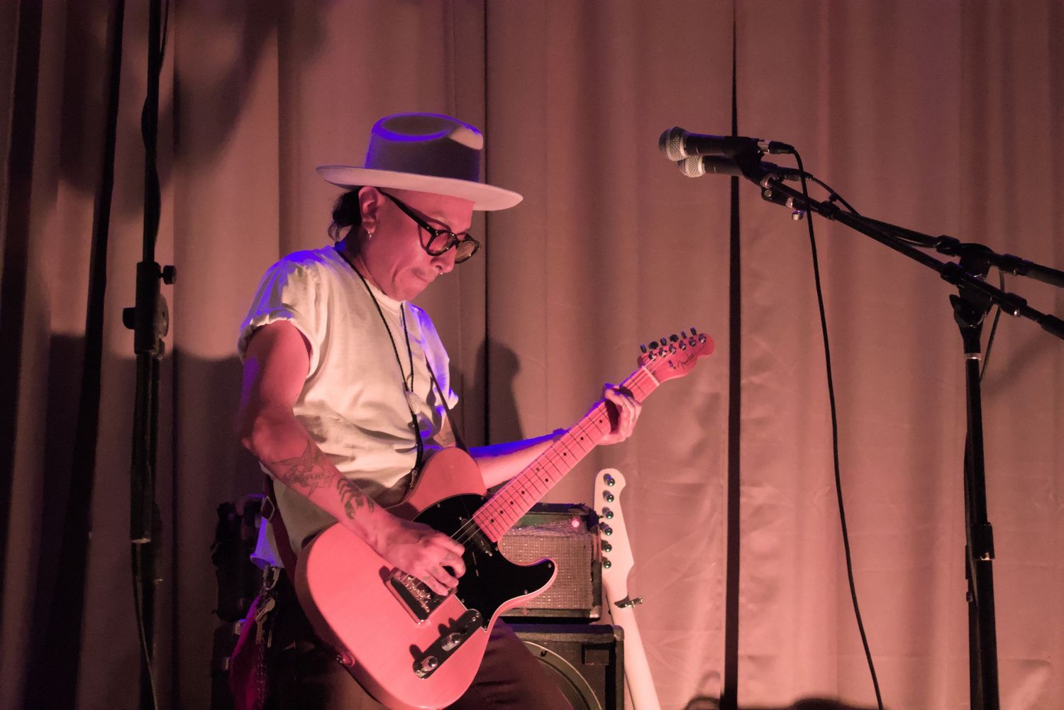 Artist in fedora playing electric guitar, showcasing creative passion and musical talent for branding.