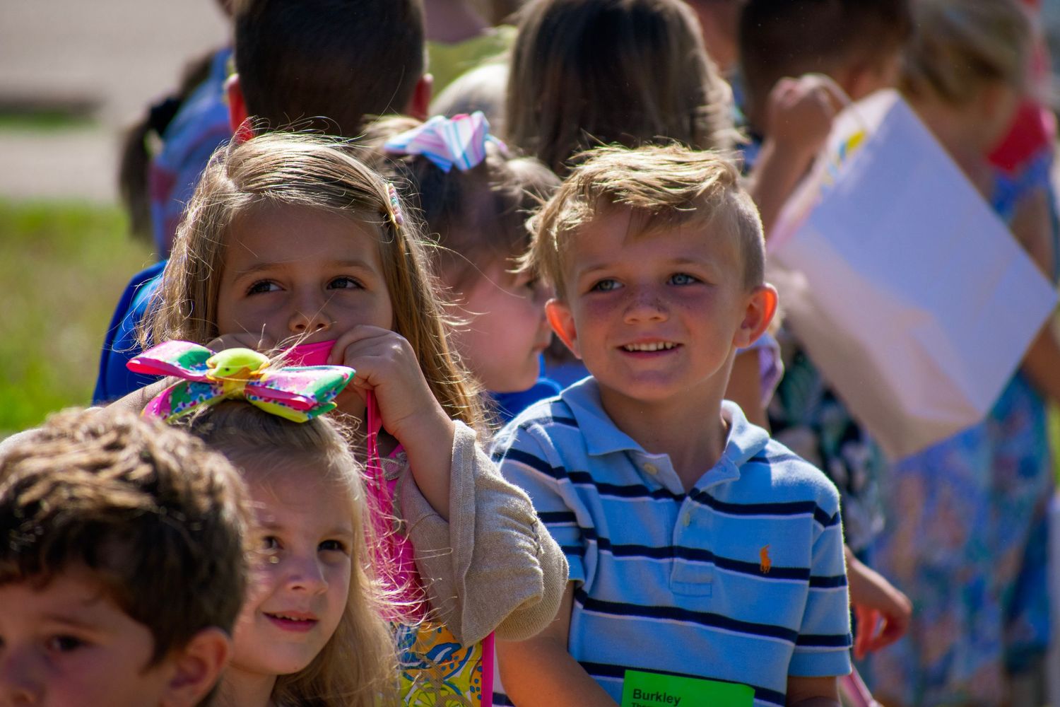 Kids smiling in a crowd at a public event. We capture the joy of family events.