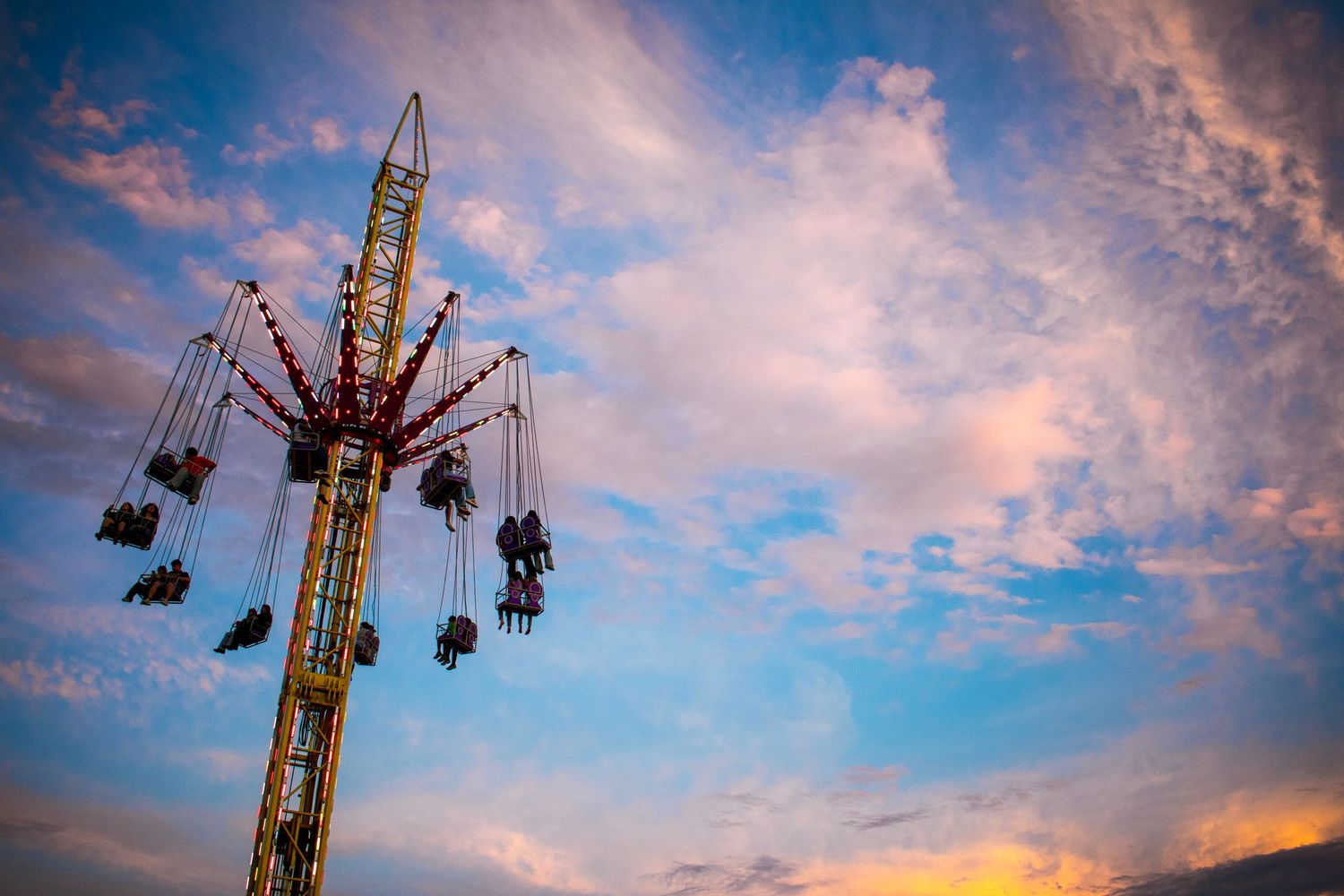 A thrilling swing ride at a Texas fair captured against a beautiful sunset. Festival photography. We capture the fun of rides & attractions