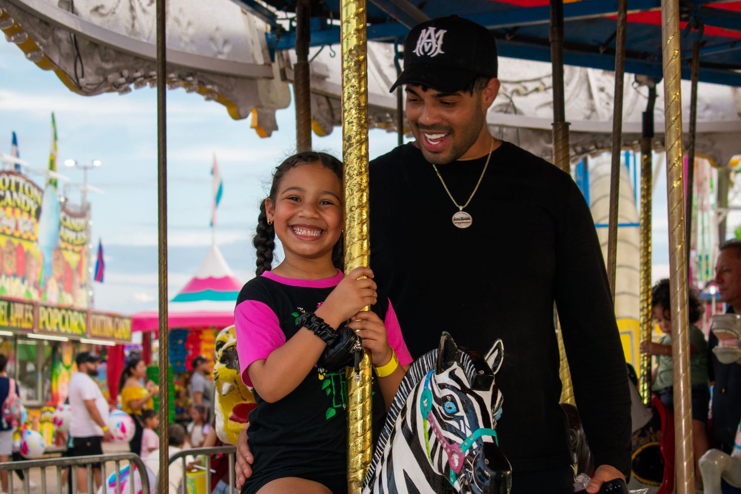 A father and daughter laugh on a carousel at a Texas fair, captured by an event photographer.