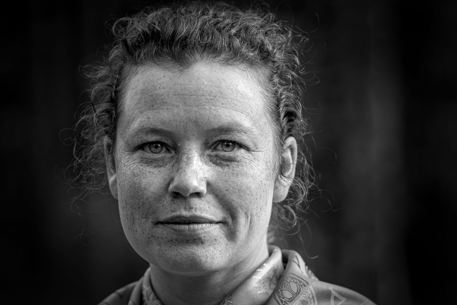 Ett närbildsporträtt i svartvitt visar en person med lockigt hår i vardagskläder.
