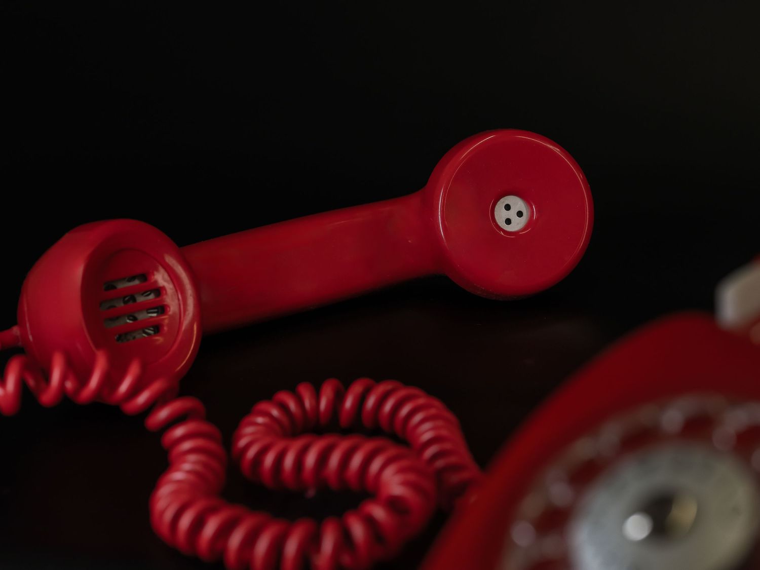 Detaljerad vy av en röd roterande telefonlur med spiralsladd.