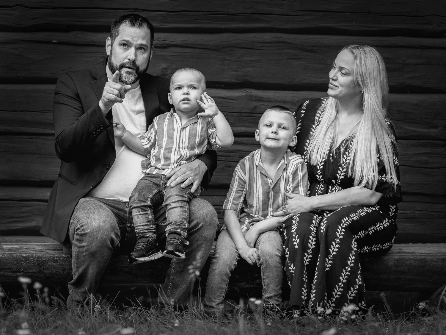 A family relaxes together on wooden steps in black and white photography.