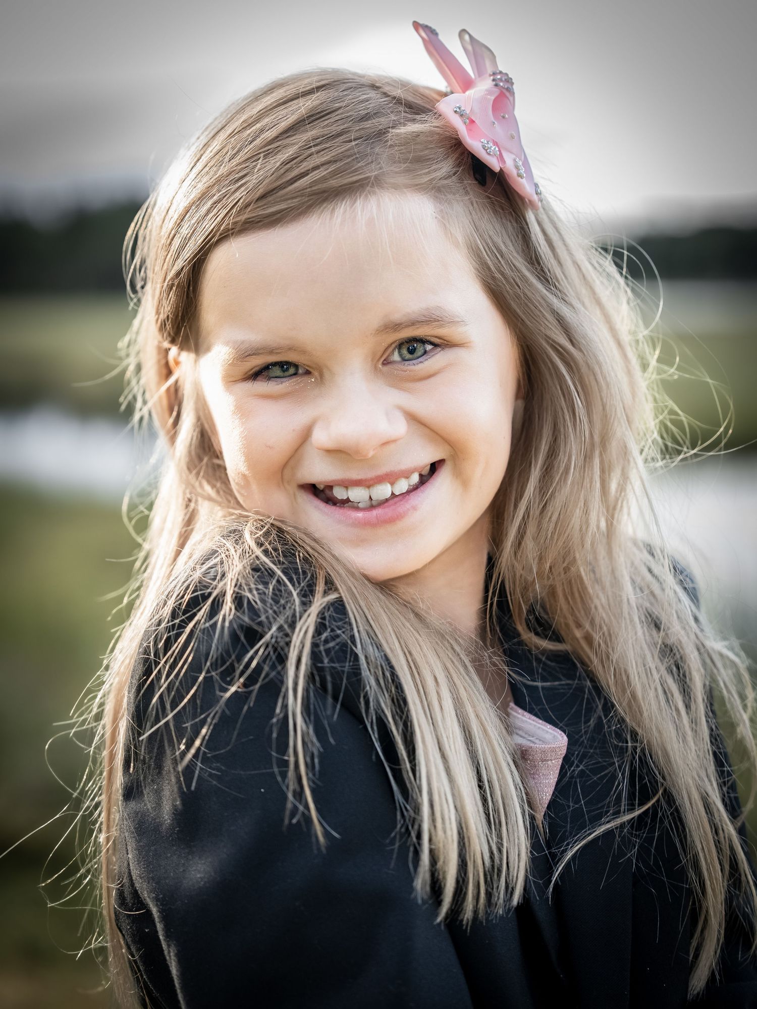 A series of close-up shots showing a child with blonde hair wearing a black top and pink bow accessory outdoors.